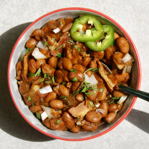 a bowl of birria pinto beans with jalapeno slices