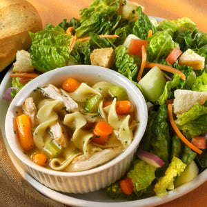 a bowl of chicken noodle soup and a fresh salad